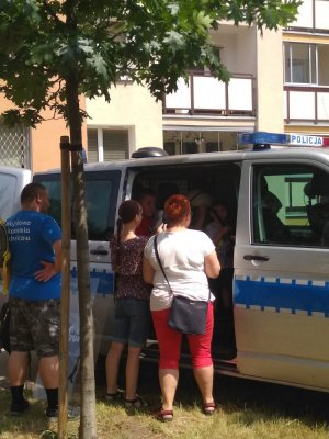 zdjęcie wykonane w plenerze, znajduje się na nim policyjny bus przed którym stoi grupka osób oglądająca go