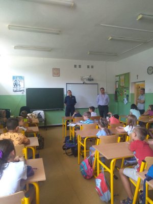 zdjęcie przedstawia salę lekcyjną, w której znajduje się policjantka i pracownik biura bezpieczeństwa i zarządzania kryzysowego, dzieci siedzą w ławkach i słuchają prelekcji