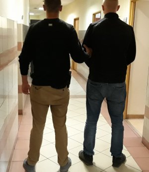 Policjant prowadzi zatrzymanego
