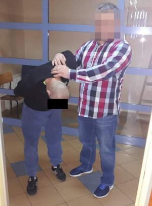 Policjant prowadzi zatrzymanego
