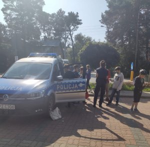 Policjantka prezentuje dzieciom radiowóz policyjny.