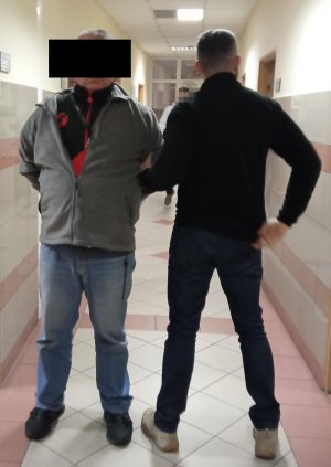 policjant prowadzi zatrzymanego