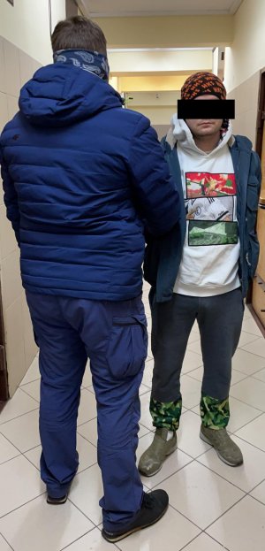 policjant prowadzi zatrzymanego