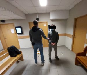 policjant doprowadza zatrzymanego na rozprawę