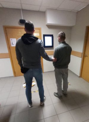 policjant doprowadza zatrzymanego na rozprawę