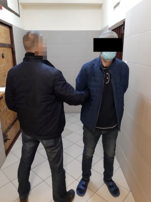 policjant prowadzi zatrzymanego