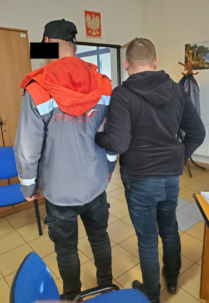 policjant wykonuje czynności z zatrzymanym