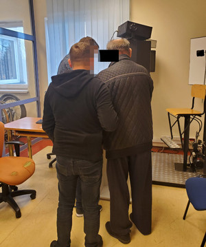 policjant wykonuje czynności z zatrzymanym